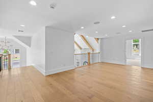 Unfurnished living room with light wood-type flooring, recessed lighting, and a chandelier