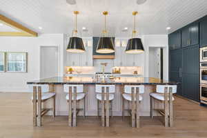 Kitchen with tasteful backsplash, light wood-style floors, glass insert cabinets, a breakfast bar area, and wooden ceiling