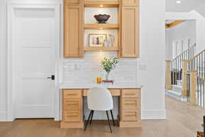 Office area with built in desk, light wood-type flooring, crown molding, and recessed lighting