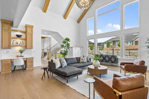 Living area with beam ceiling, light wood finished floors, a desk, a chandelier, and high vaulted ceiling