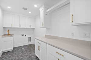 Washroom featuring hookup for a washing machine, electric dryer hookup, recessed lighting, cabinet space, and dark tile patterned flooring