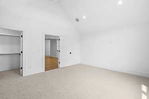 Unfurnished bedroom featuring carpet, recessed lighting, high vaulted ceiling, a spacious closet, and beam ceiling