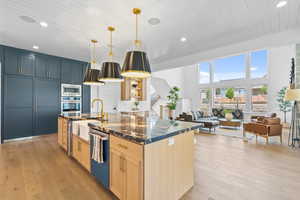 Kitchen featuring light wood-style floors, recessed lighting, light brown cabinets, a center island with sink, and dark stone counters