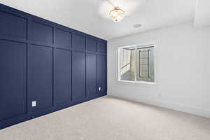 Unfurnished bedroom with carpet floors and a decorative wall
