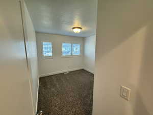 Unfurnished room featuring a textured ceiling and dark colored carpet