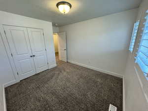 Unfurnished bedroom with carpet floors, a closet, and a textured ceiling