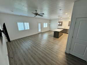 Unfurnished living room featuring a textured ceiling, ceiling fan, wood finished floors, and recessed lighting