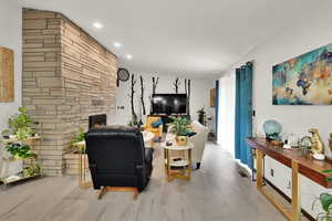 Living room with wood finished floors and a stone fireplace