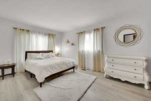Bedroom with multiple windows and light wood-style floors