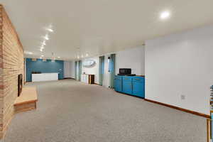 Finished basement with light carpet, recessed lighting, and a fireplace