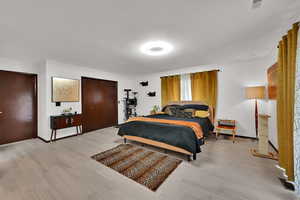 Bedroom with light wood-style floors, a textured ceiling, and a closet