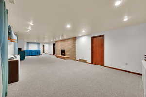 Unfurnished living room with carpet flooring, a stone fireplace, and recessed lighting