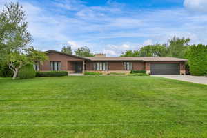View of front of home with a garage, concrete driveway, a front lawn, and a chimney