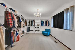 Walk in closet with wood finished floors and a chandelier