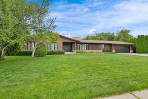 View of front of house featuring a garage, a front lawn, a chimney, and driveway