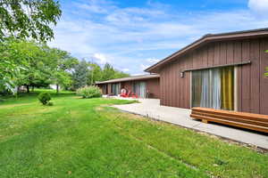 View of grassy yard with a patio area