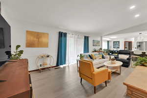 Living room with light wood-style flooring, recessed lighting, and vaulted ceiling