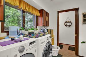 Laundry room with washing machine and dryer, cabinet space, and light tile patterned floors