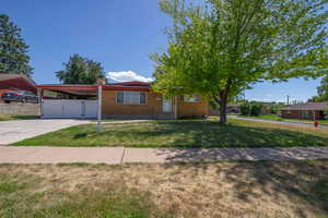 Single story home featuring brick siding, a gate, concrete driveway, a carport, and a chimney