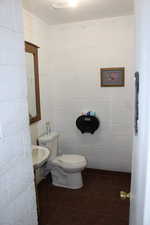 Bathroom featuring tile patterned flooring, ornamental molding, and concrete block wall