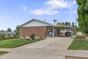 View of side of home featuring a carport, concrete driveway, and brick siding