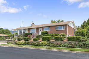 Single story home featuring a chimney and brick siding