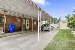 View of parking / parking lot with an attached carport, a storage unit, and driveway