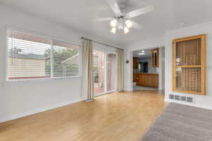 Unfurnished living room featuring a ceiling fan and light wood-style floors