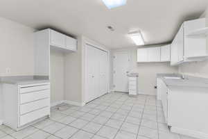 Kitchen featuring open shelves, white cabinetry, light countertops, and light tile patterned floors