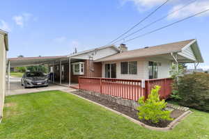 Rear view of house featuring an attached carport, a lawn, and a chimney