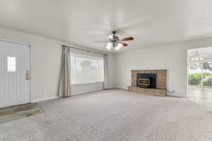 Unfurnished living room featuring a ceiling fan, healthy amount of natural light, carpet flooring, and a textured ceiling