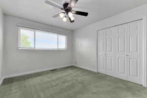 Unfurnished bedroom featuring carpet, a closet, and a ceiling fan