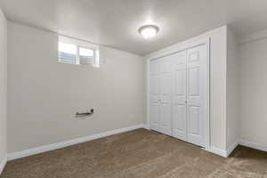 Unfurnished bedroom featuring a textured ceiling, carpet, and a closet