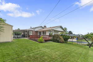 Rear view of property featuring a carport, a yard, and a deck