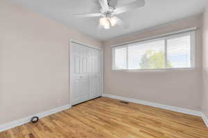 Unfurnished bedroom with light wood-style floors, a closet, and ceiling fan