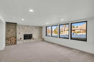 Unfurnished living room featuring recessed lighting, carpet, an accent wall, and a fireplace