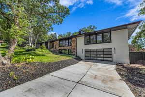 View of front facade featuring driveway, a garage, a front yard, and brick siding
