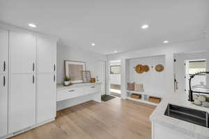 Kitchen featuring light wood-style flooring, white cabinetry, light stone countertops, and recessed lighting