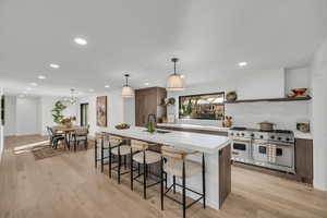 Kitchen featuring open shelves, double oven range, light countertops, light wood-style floors, and recessed lighting