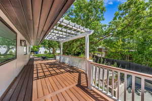 Wooden deck with a pergola and view of wooded area