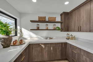 Kitchen featuring open shelves, dark brown cabinetry, recessed lighting, and light stone counters
