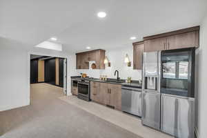 Kitchen with stainless steel appliances, dark countertops, light colored carpet, and recessed lighting