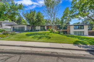 Mid-century home featuring an attached garage, a front yard, and driveway