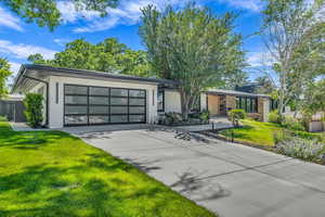 View of front of property featuring concrete driveway, an attached garage, and stone siding