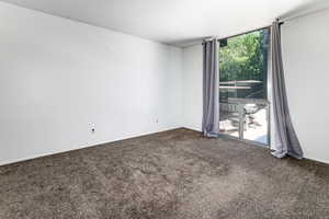 Empty room featuring dark colored carpet and baseboards