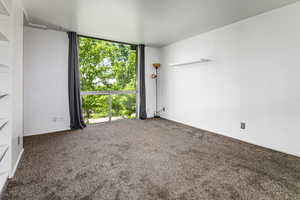 Carpeted spare room featuring a wall of windows and baseboards