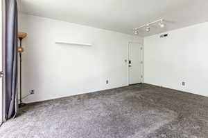 Carpeted spare room featuring track lighting