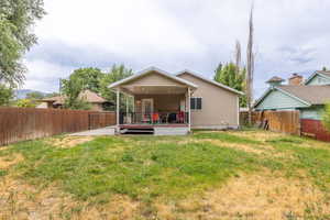 Rear view of house with a fully fenced backyard and a large covered deck