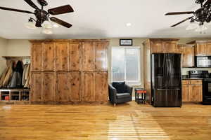 Kitchen featuring a ceiling fan, black appliances, light hardwood flooring, brown wooden cabinetry, and a textured ceiling