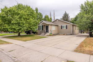 View of front facade featuring large concrete driveway and a front yard
